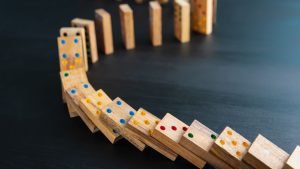 Stacked dominos with colored dots falling - showing choices have consequences